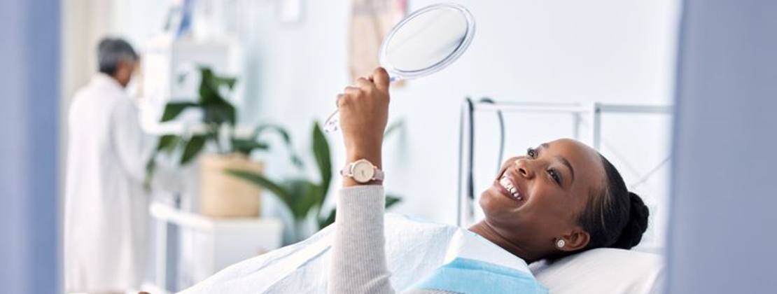 Patient holding mirror and smiling at herself