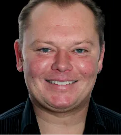 Man in a black collared shirt smiling