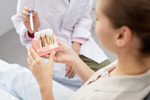 A woman displays a tooth model in her hand, illustrating dental health concepts.