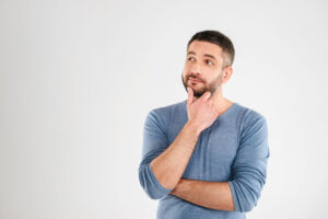 A man with a pensive expression, resting his chin on his hand, appears deep in thought.