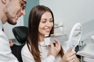 A woman beams with a smile while a man gazes at her teeth, showing interest.